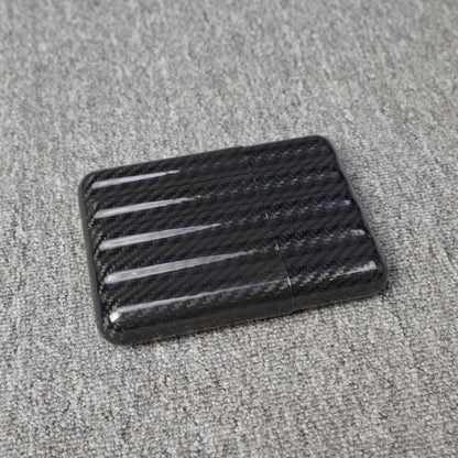 Close-up of a carbon fiber cigar case with a capacity for 5 cigars, featuring a distinct woven pattern, placed on a gray fabric surface.