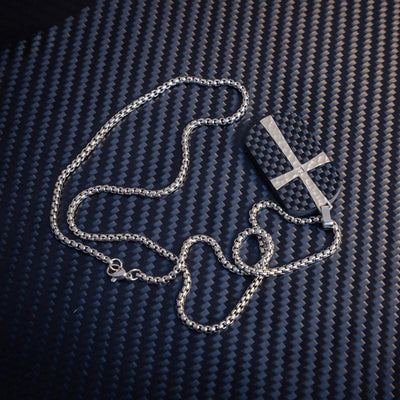 Close-up of a 3K carbon fiber pendant featuring a silver cross accent with a small diamond detail, paired with a silver-tone chain