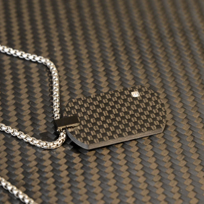 Close-up of a 3K carbon fiber dog tag pendant with a checkered pattern and a small diamond accent, paired with a silver-tone chain