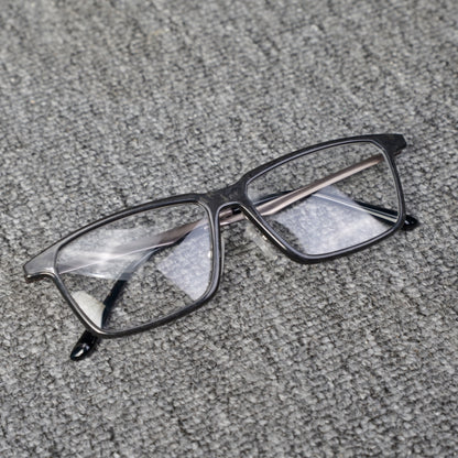 Close-up of a forged carbon fiber eyeglass frame with a sleek black design and clear lenses, placed on a textured gray surface.