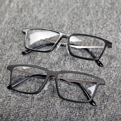 Close-up of two eyeglass frames featuring forged carbon fiber and 3K carbon fiber constructions, with sleek black designs and clear lenses