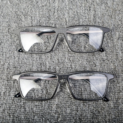 Close-up of two pairs of eyeglass frames crafted from forged carbon fiber and 3K carbon fiber, showcasing sleek black designs with clear lenses