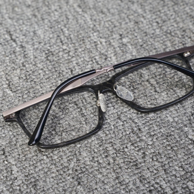 Close-up reverse side detail of a forged carbon fiber eyeglass frame, featuring clear nose pads and black with metallic temples