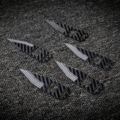 Close-up of five 3K carbon fiber knives with checkered patterns, striped blades, and cutout details, arranged on a dark textured fabric surface.