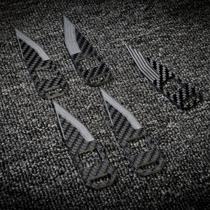 Close-up of five 3K carbon fiber knives with checkered patterns and varied cutout designs, arranged on a dark textured fabric surface.