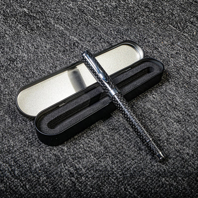 Close-up of a carbon fiber ballpoint pen with a distinct woven texture, paired with a black metal case featuring foam lining