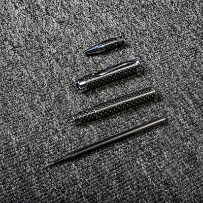 Close-up of a carbon fiber ballpoint pen disassembled into its components, showcasing the distinct woven texture and metallic accents