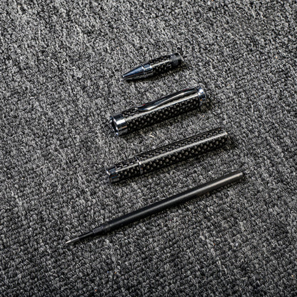 Close-up of a carbon fiber ballpoint pen disassembled into its components, showcasing the distinct woven texture and metallic accents, displayed on a gray textured fabric surface.
