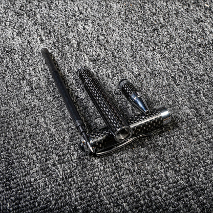 Close-up of a disassembled carbon fiber ballpoint pen with distinct woven texture and metallic accents, displayed on a gray textured fabric surface.