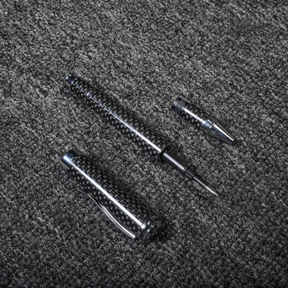 Close-up of a disassembled carbon fiber ballpoint pen with a distinct woven texture and metallic accents, displayed on a gray textured fabric surface.