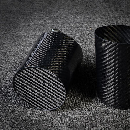 Two carbon fiber pen holders with distinct woven patterns, displayed on a gray textured surface.