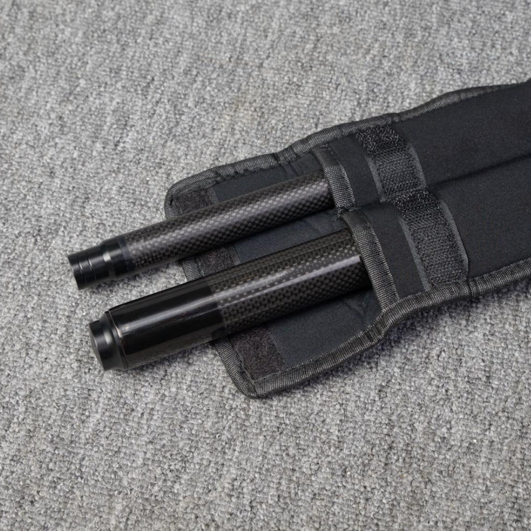 Two carbon fiber pool cue sections secured in a black fabric case, placed on a gray textured surface.
