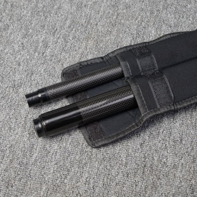 Two carbon fiber pool cue sections secured in a black fabric case, placed on a gray textured surface.