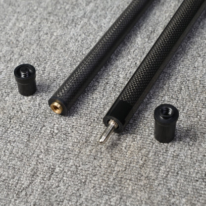 Close-up detail of a two-piece carbon fiber pool cue with a textured carbon fiber pattern, displaying the connecting components, placed on a gray textured surface.