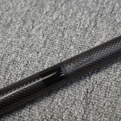 Close-up detail of a two-piece carbon fiber pool cue showcasing the connection area with a textured carbon fiber pattern, placed on a gray textured surface.