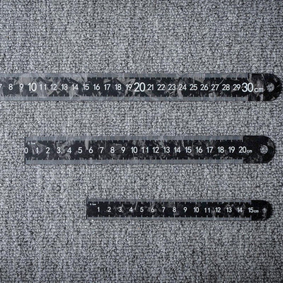 Three forged carbon fiber rulers with distinct lengths and clear measurement markings, placed on a textured surface.