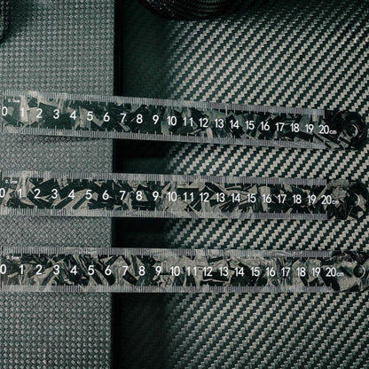 Three forged carbon fiber rulers with distinct patterns and clear measurement markings up to 20 cm, placed on a carbon fiber textured surface.