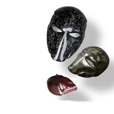 Close-up of multiple carbon fiber tactical masks in various styles — including camouflage, glossy black, and red carbon fiber patterns.