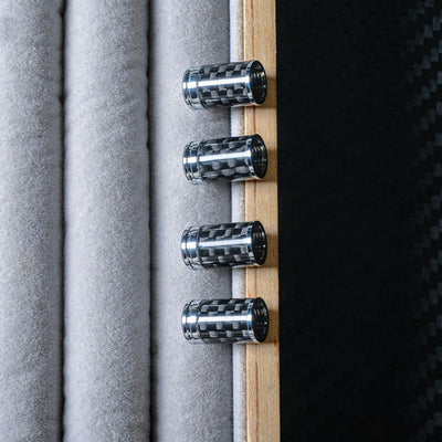 Close-up of four carbon fiber car tire valve stem caps with chrome accents, arranged vertically