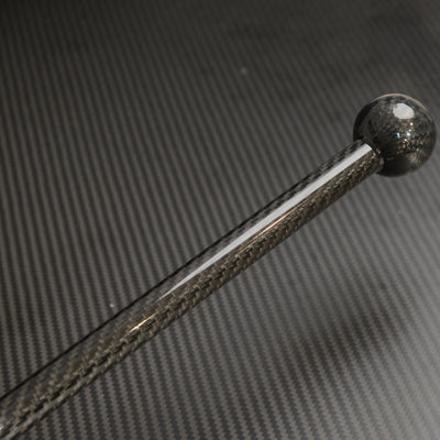 Close-up detail of a carbon fiber walking stick with a spherical top, showcasing the carbon fiber weave pattern