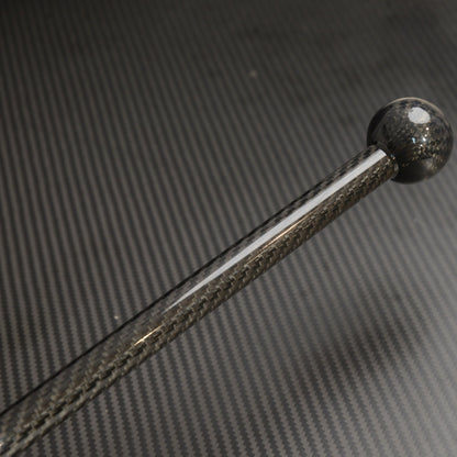Close-up detail of a carbon fiber walking stick with a spherical top, showcasing the carbon fiber weave pattern, placed against a carbon fiber textured background.