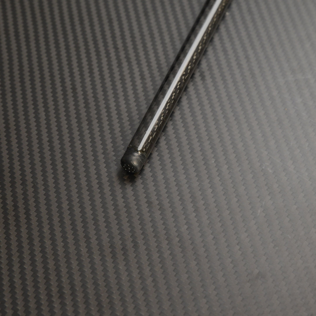 Close-up of the bottom part of a carbon fiber cane, showcasing the detailed carbon fiber weave pattern, placed on a carbon fiber textured surface.