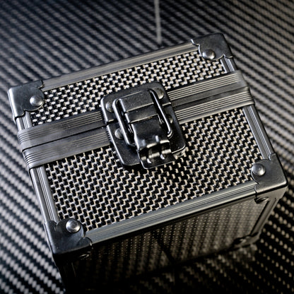 Close-up of a 3K carbon fiber watch box with a checkered pattern, a metallic latch, and reinforced metallic corners, positioned on a carbon fiber textured surface.