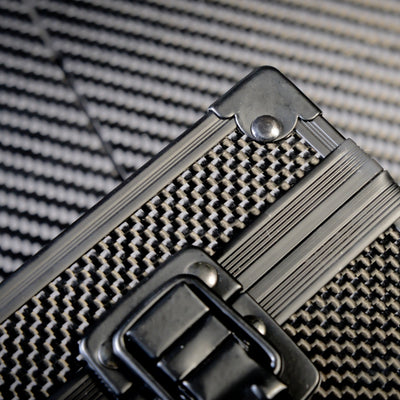 Close-up of the front of a 3K carbon fiber watch box featuring a checkered pattern, a black metallic latch, and metallic rivets with trim