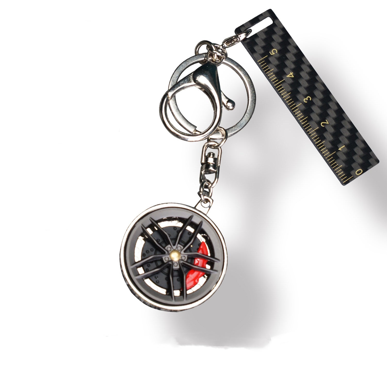 A close-up shot reveals a carbon fiber key fob featuring a wheel-inspired design paired with vibrant red brake calipers, accented by carbon fiber texture details (including a trim strip engraved with ruler markings).