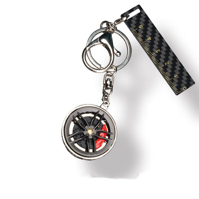 A close-up shot reveals a carbon fiber key fob featuring a wheel-inspired design paired with vibrant red brake calipers