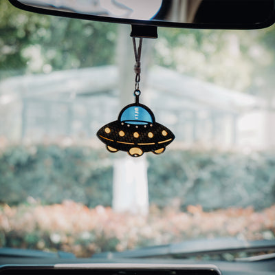 UFO-shaped car rearview mirror hanging accessory: Black carbon fiber-textured saucer body, bright blue cockpit section