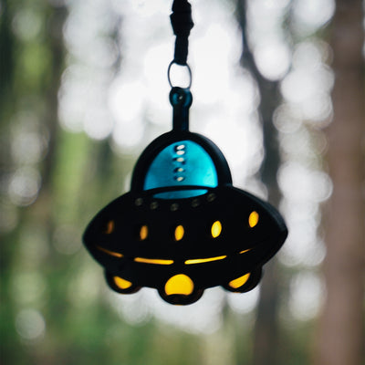 Hanging UFO-shaped accessory : Features a black textured body, a glossy bright blue cockpit section